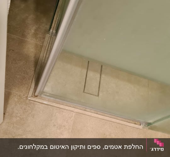 דלת זכוכית למקלחת על רצפת אריחים